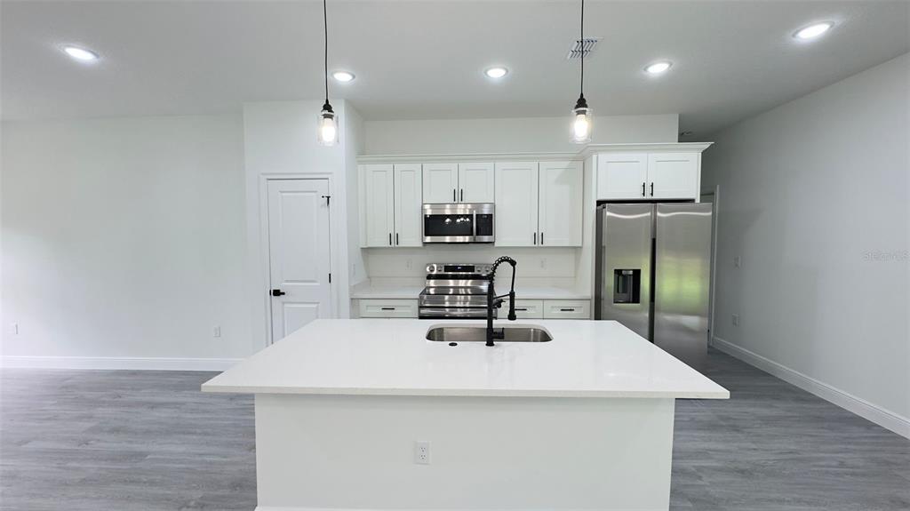 A modern kitchen features white cabinetry, stainless steel appliances, and a large central island — 2827 W XENOX DRIVE, CITRUS SPRINGS, FL