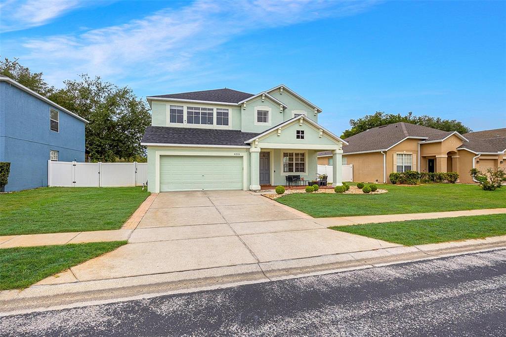A two-story light green house with a two-car garage and a front porch — 4215 MAPLEHURST WAY, SPRING HILL, FL