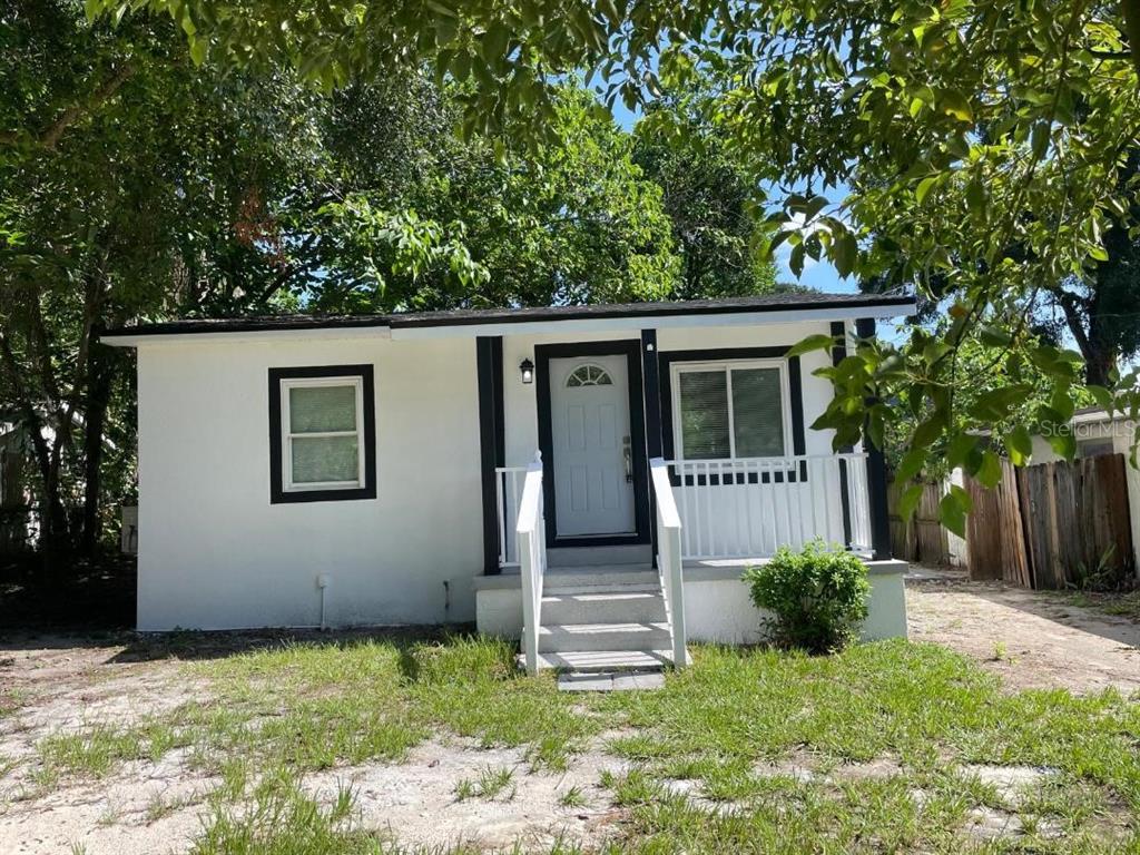 A small, white, single-story house with black trim and a front porch with stairs — 1812 E OKALOOSA AVENUE, TAMPA, FL