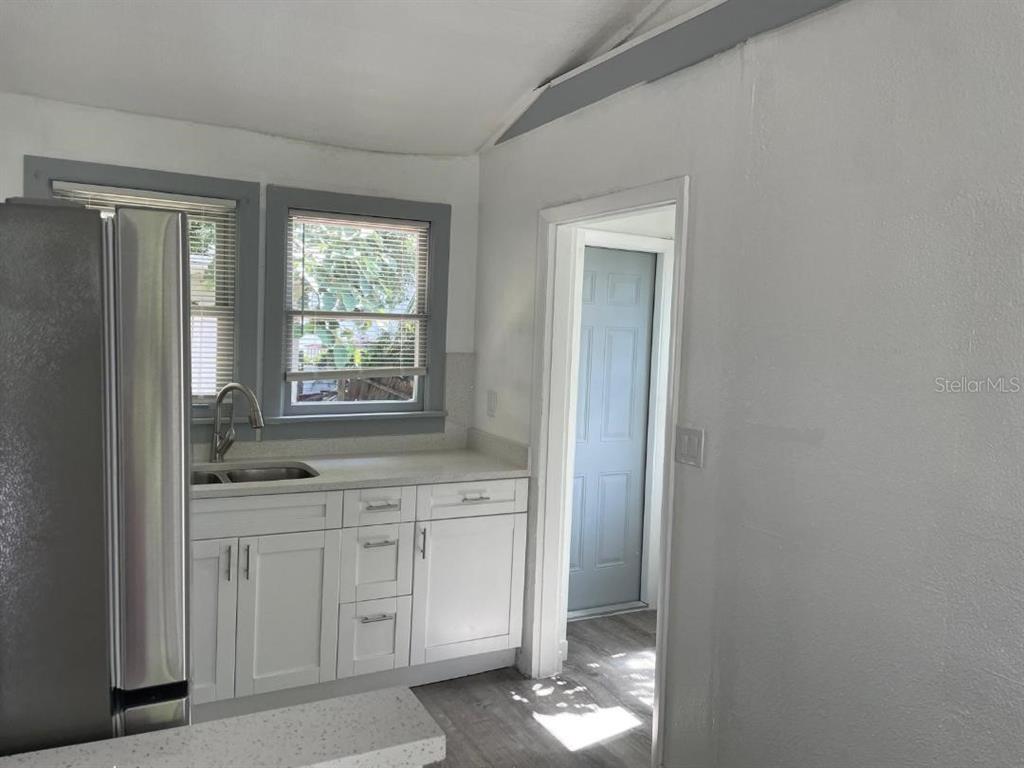 A kitchen with white cabinets, a stainless steel refrigerator, and a doorway leading outside — 1812 E OKALOOSA AVENUE, TAMPA, FL