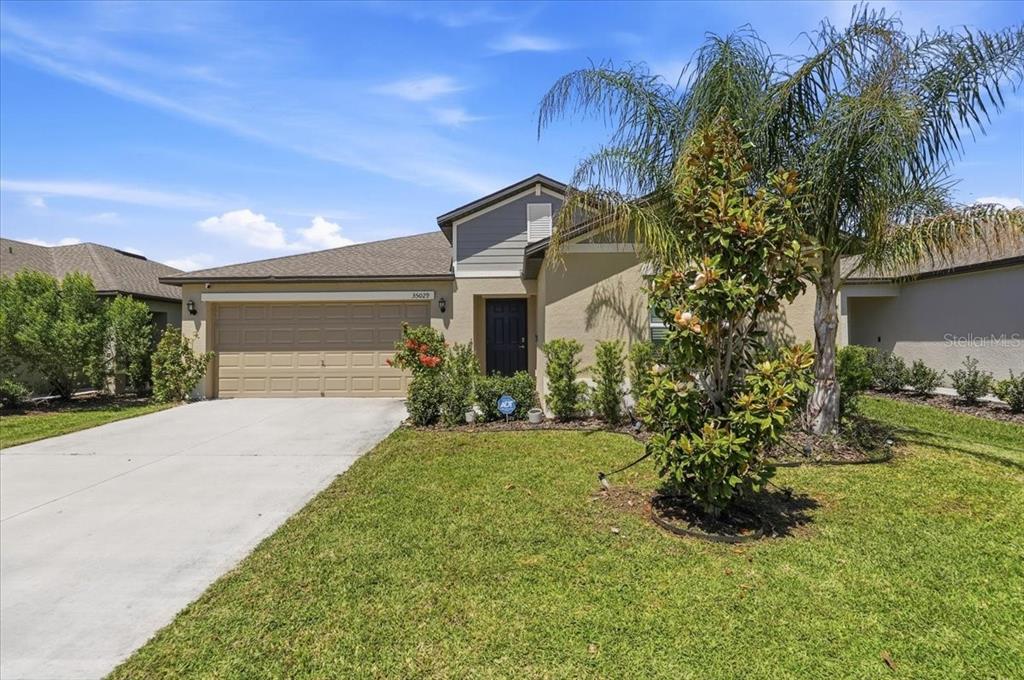 A single-story house with a beige stucco exterior, a two-car garage, and a front lawn — 35029 BRACKETT BEND, ZEPHYRHILLS, FL