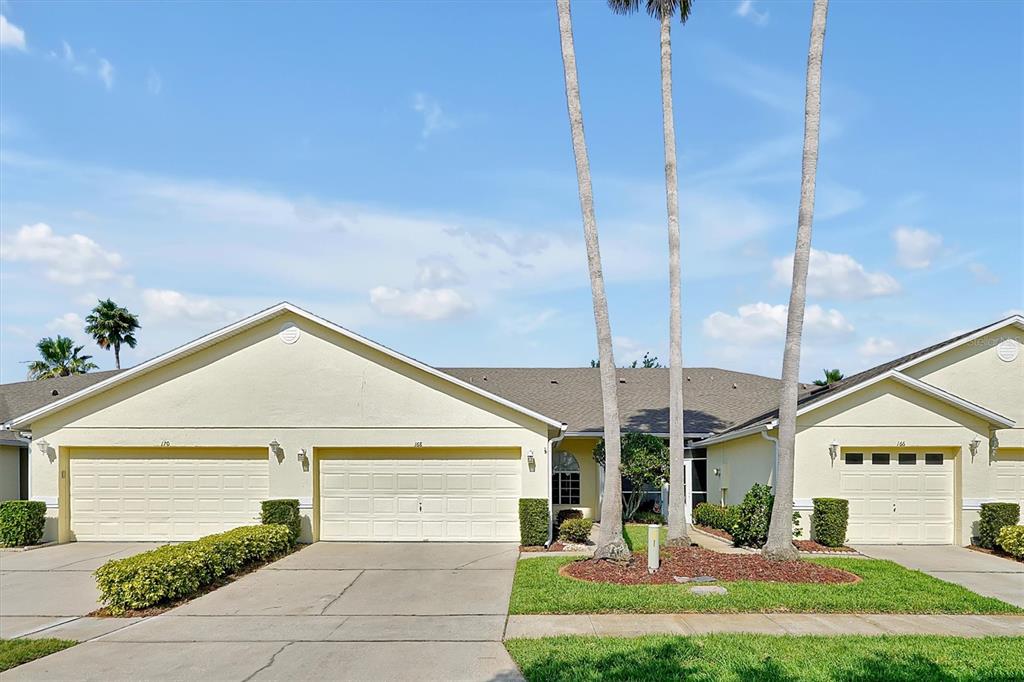 A view of the exterior of a single-story residential building with three attached garages — 168 CLUB VILLAS LANE, KISSIMMEE, FL