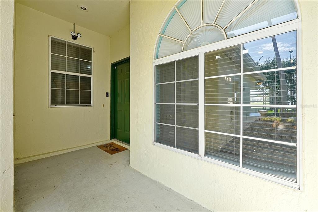 A covered entryway features a green door, a large arched window, and concrete flooring — 168 CLUB VILLAS LANE, KISSIMMEE, FL