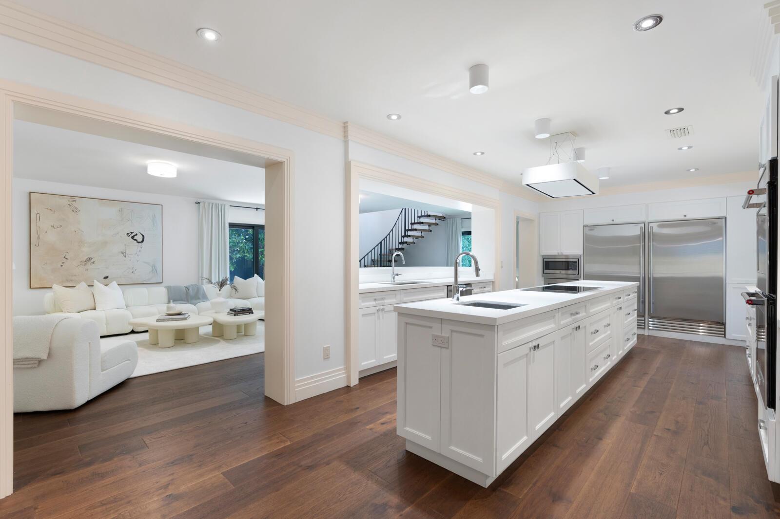 A modern white kitchen with a large island and stainless steel appliances opens to a living room — 1435 N Ocean Way, Palm Beach FL 33480, PALM BEACH, FL