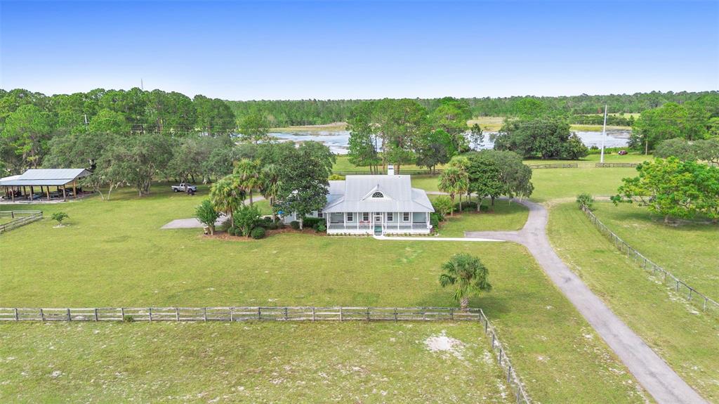 An aerial view shows a white house with a metal roof surrounded by green pastures — 42554 MAGGIE JONES ROAD, PAISLEY, FL