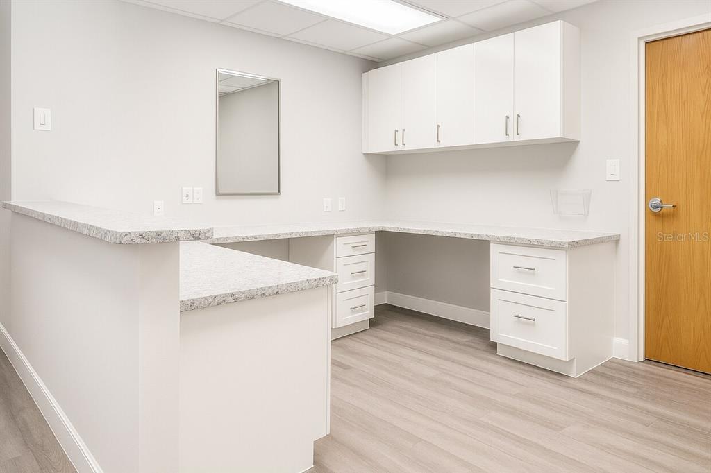 A bright office space features white cabinetry, granite countertops, and light wood-look flooring — 14100 FIVAY ROAD UNIT 120, HUDSON, FL
