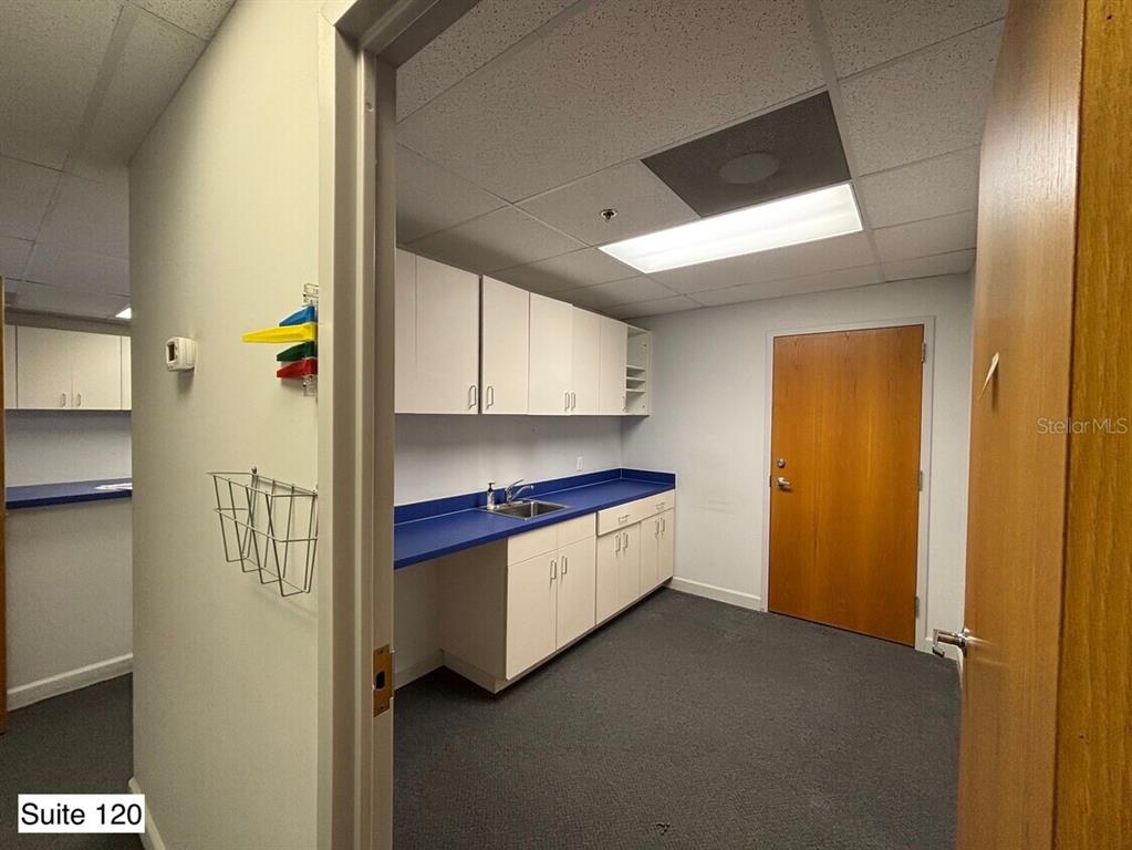 A small office breakroom features white cabinets, a blue countertop with a sink, and carpet — 14100 FIVAY ROAD UNIT 120, HUDSON, FL