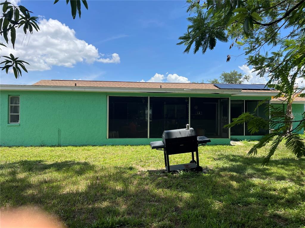 A green house exterior features a screened-in porch and a charcoal grill on the lawn — 644 ERROLL STREET, PORT CHARLOTTE, FL