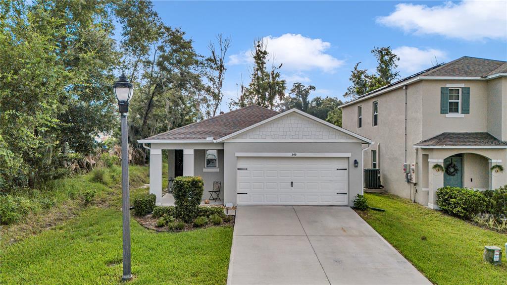 A single-story house with a gray stucco exterior, a two-car garage, and a covered entryway — 345 PELHAM PARK DRIVE, DELAND, FL