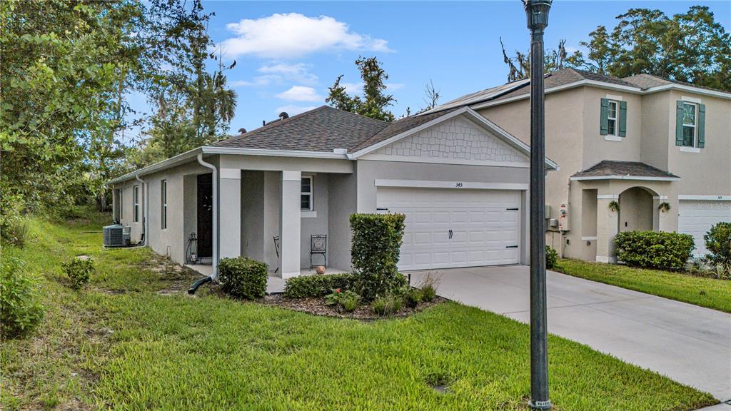 A covered concrete patio area attached to the side of a beige stucco house — 345 PELHAM PARK DRIVE, DELAND, FL