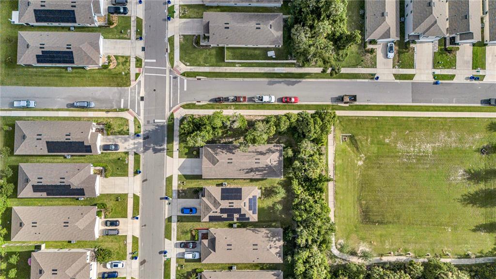 An aerial view shows a suburban neighborhood with houses, streets, and an adjacent grassy lot — 345 PELHAM PARK DRIVE, DELAND, FL