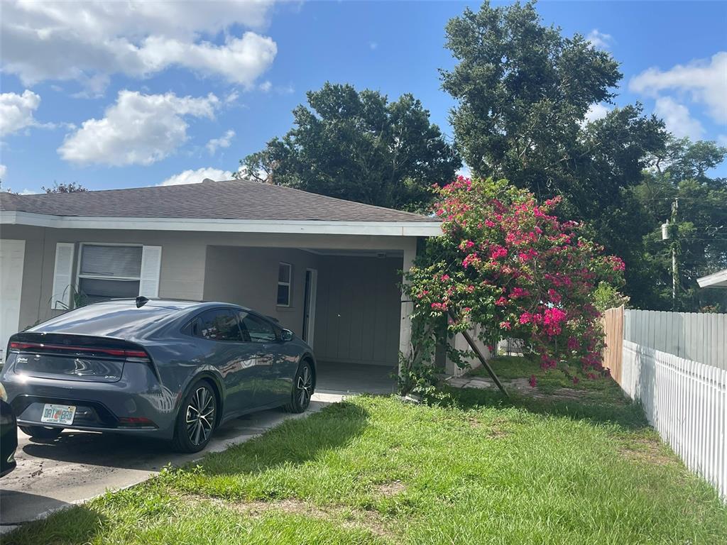 A gray sedan is parked in the carport of a single-story house with pink bougainvillea — 3305 13TH AVENUE W, BRADENTON, FL