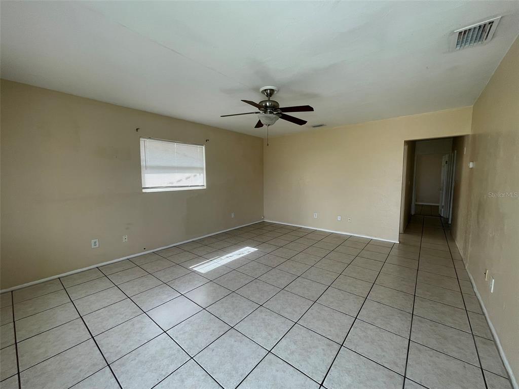 An empty room features beige walls, a ceiling fan, and light-colored square floor tiles — 3305 13TH AVENUE W, BRADENTON, FL