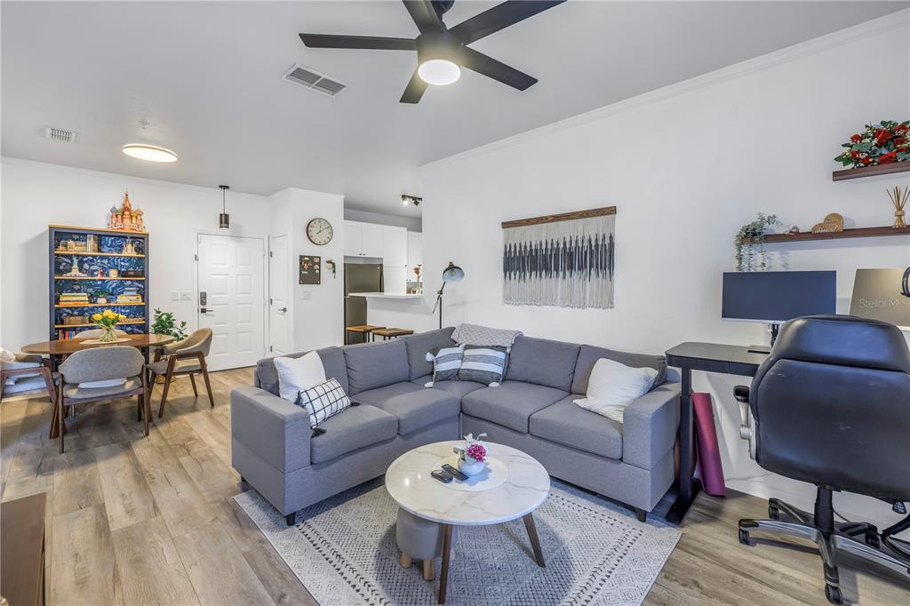 A living room features a grey sectional sofa, a round coffee table, and a desk area — 4221 W SPRUCE STREET UNIT 1325, TAMPA, FL