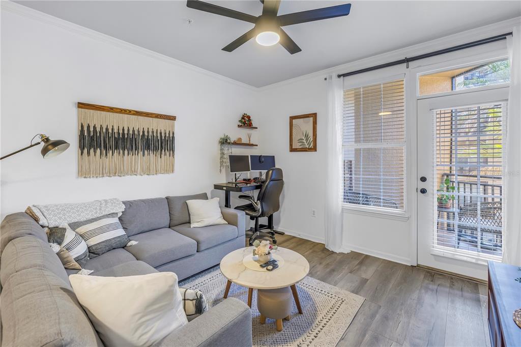 A living room features a gray sectional sofa, a desk area, and a glass door — 4221 W SPRUCE STREET UNIT 1325, TAMPA, FL