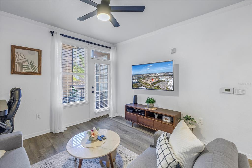 A living room features a ceiling fan, a wall-mounted television, and a glass door — 4221 W SPRUCE STREET UNIT 1325, TAMPA, FL