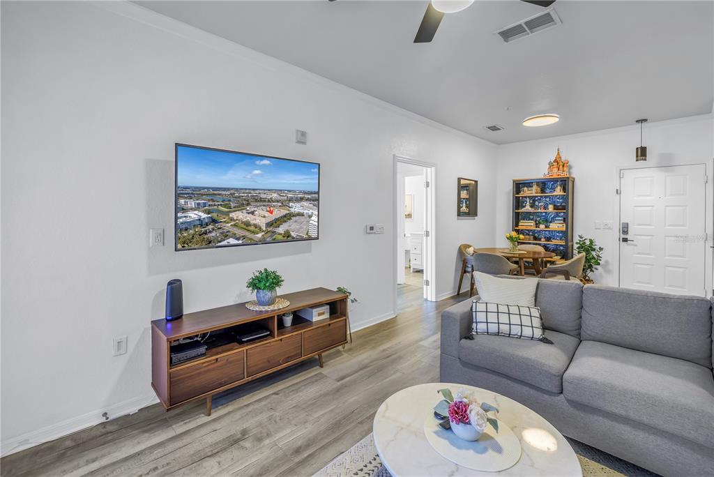 A living room features a wall-mounted television, a wooden media console, and a gray sofa — 4221 W SPRUCE STREET UNIT 1325, TAMPA, FL