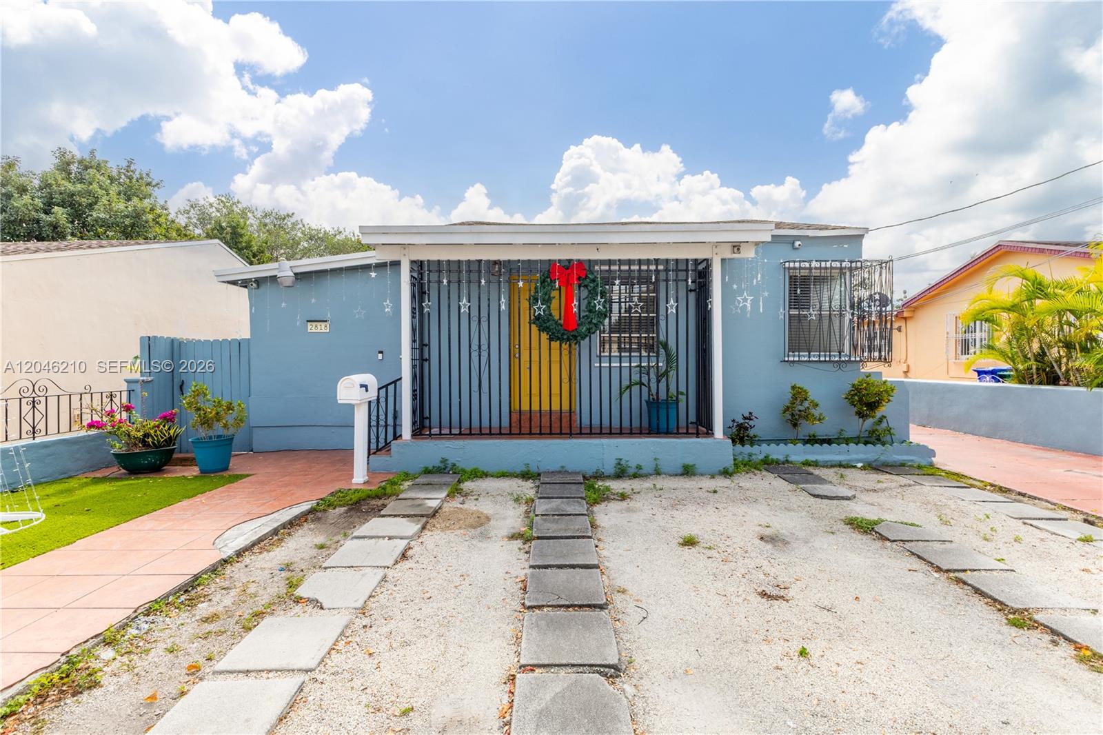 A light blue single-story house features a gated front porch and a gravel driveway — 2818 SW 2nd St, Miami FL 33135, MIAMI, FL