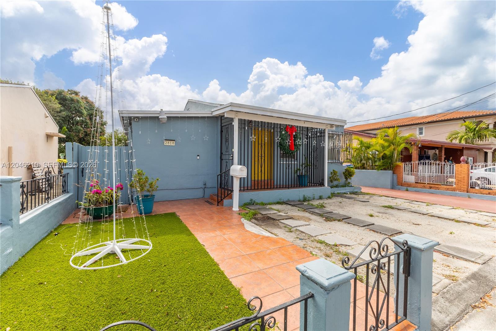 A light blue single-story house features a tiled walkway, artificial grass, and a metal gate — 2818 SW 2nd St, Miami FL 33135, MIAMI, FL