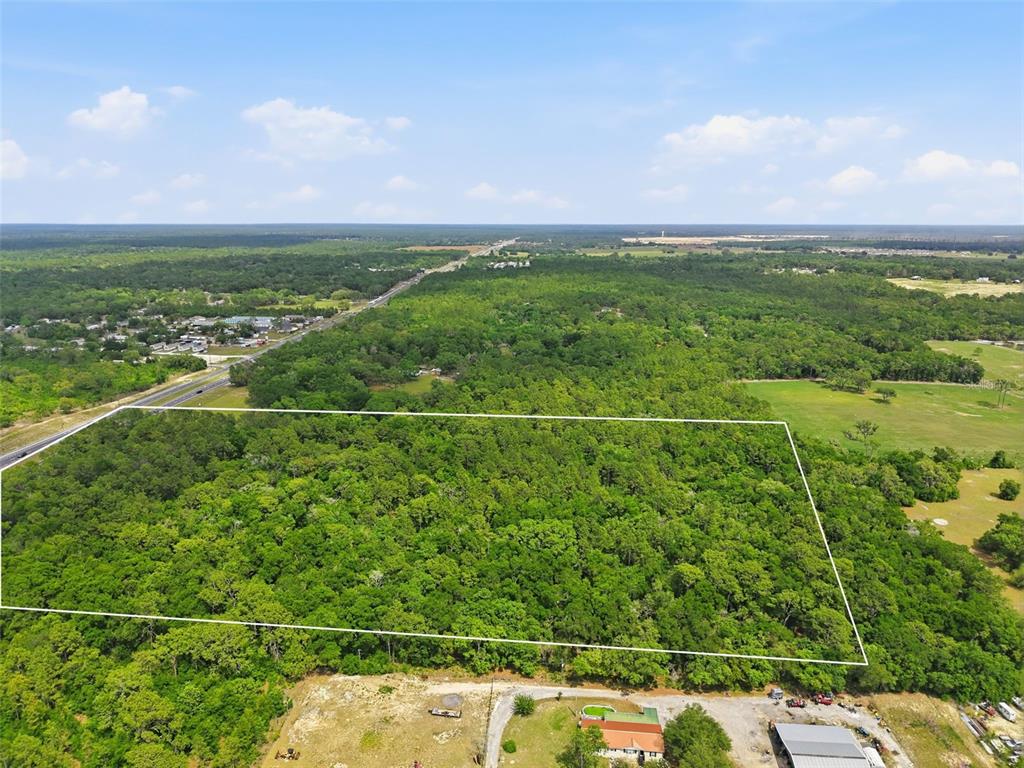 An aerial view shows a large, rectangular wooded lot outlined in white near a highway — CORTEZ BOULEVARD, BROOKSVILLE, FL