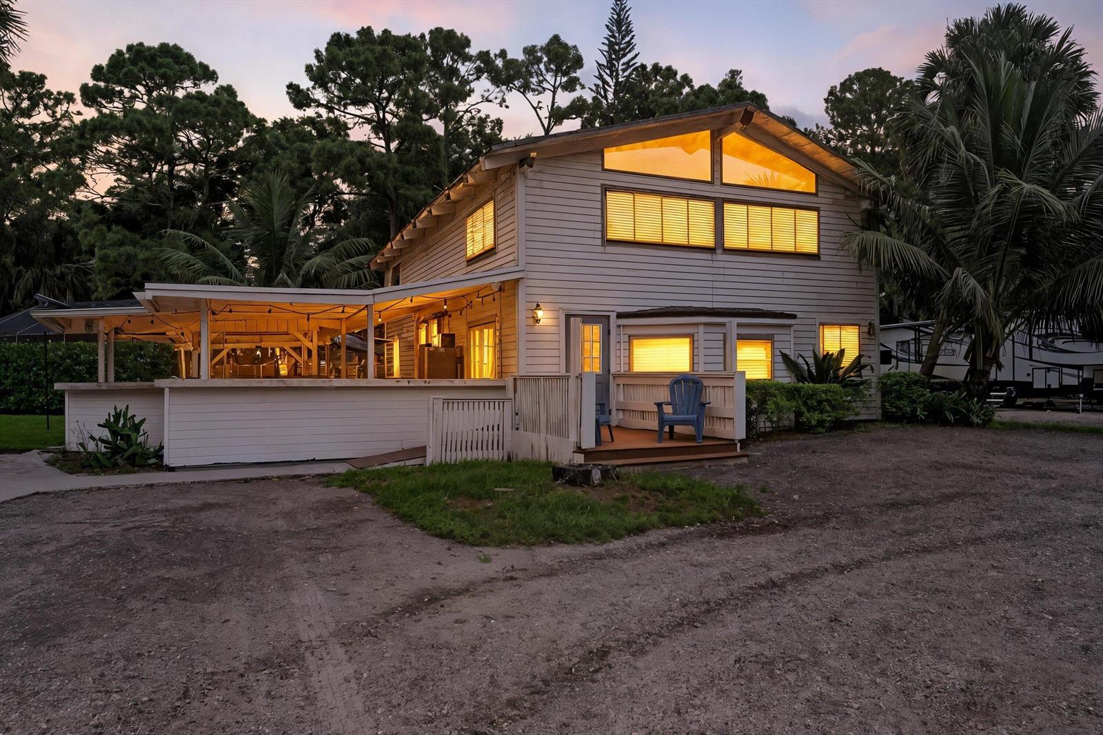 A two-story house with a covered patio, wooden siding, and large windows at dusk — 2915 Doe Trail, FL 33470, FL