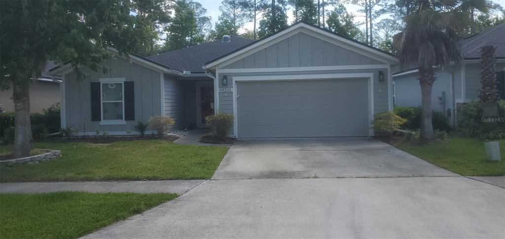 A single-story house with light gray siding, a two-car garage, and a concrete driveway — 95236 SIENA COURT, FERNANDINA BEACH, FL