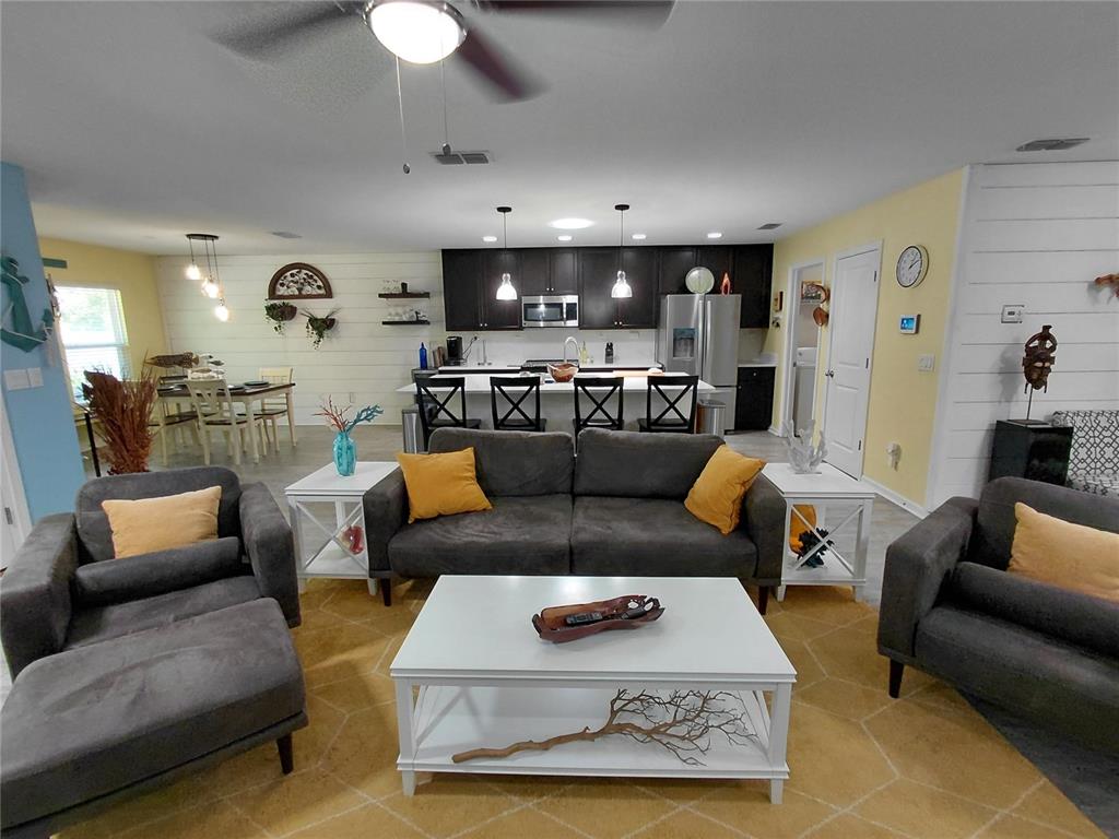 A living room with gray sofas and a white coffee table faces an open kitchen — 95236 SIENA COURT, FERNANDINA BEACH, FL