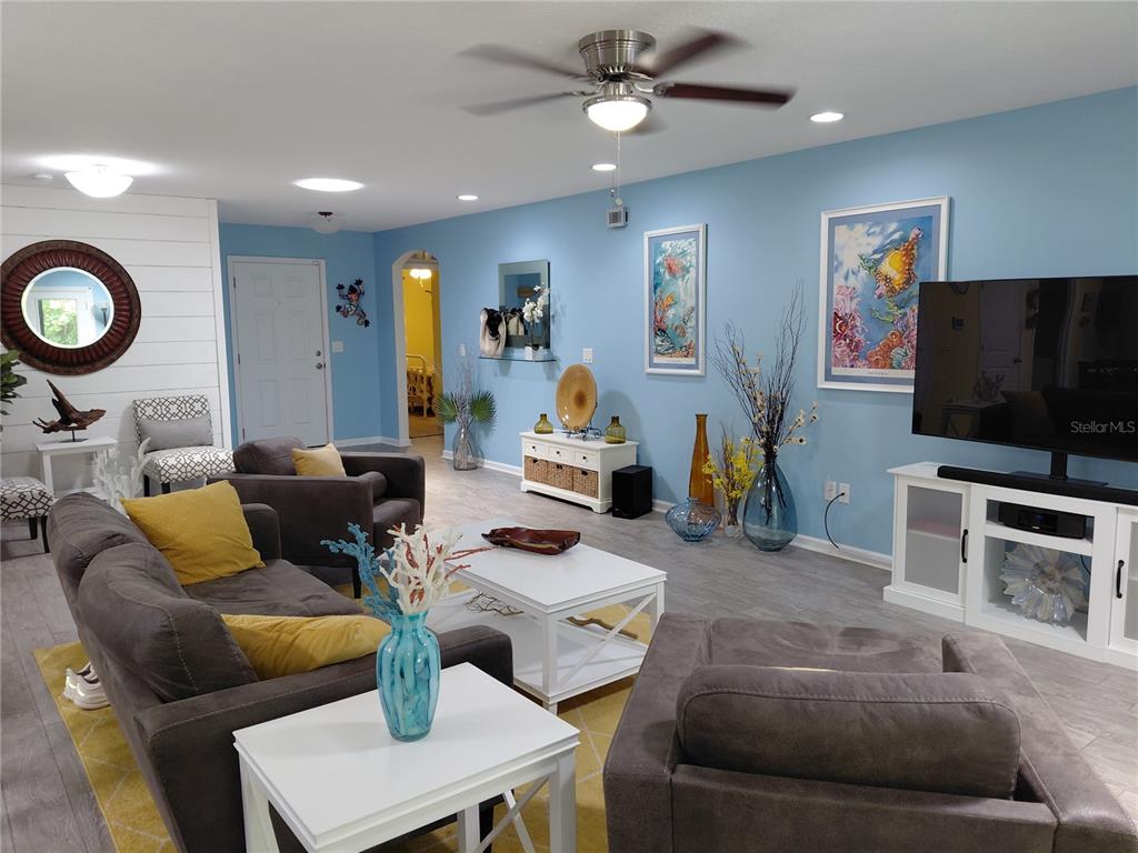 A living room features light blue walls, gray flooring, a ceiling fan, and white furniture — 95236 SIENA COURT, FERNANDINA BEACH, FL