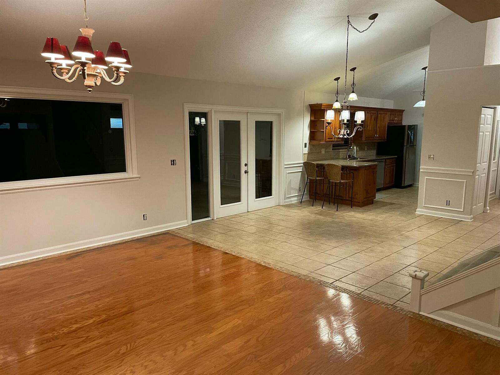 A living area with hardwood floors transitions into a tiled kitchen with wooden cabinets — 232 Maplecrest Circle, Jupiter FL 33458, JUPITER, FL