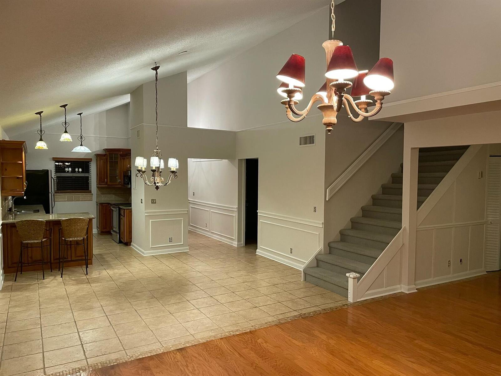 An open-concept living area features a kitchen with bar seating, tile flooring, and a staircase — 232 Maplecrest Circle, Jupiter FL 33458, JUPITER, FL