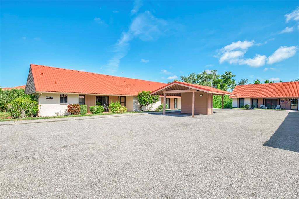 A low-rise building with a bright orange roof and a covered carport area — 6698 DRAW LANE UNIT 140, SARASOTA, FL