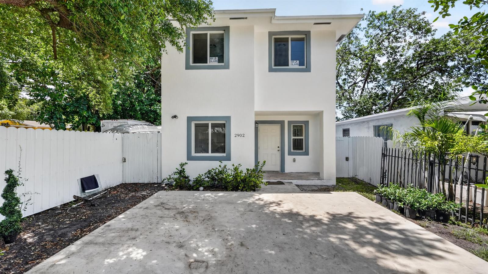 A two-story white house with gray window trim and a concrete driveway in front — 2902 NW 44th Street, Miami FL 33142, MIAMI, FL