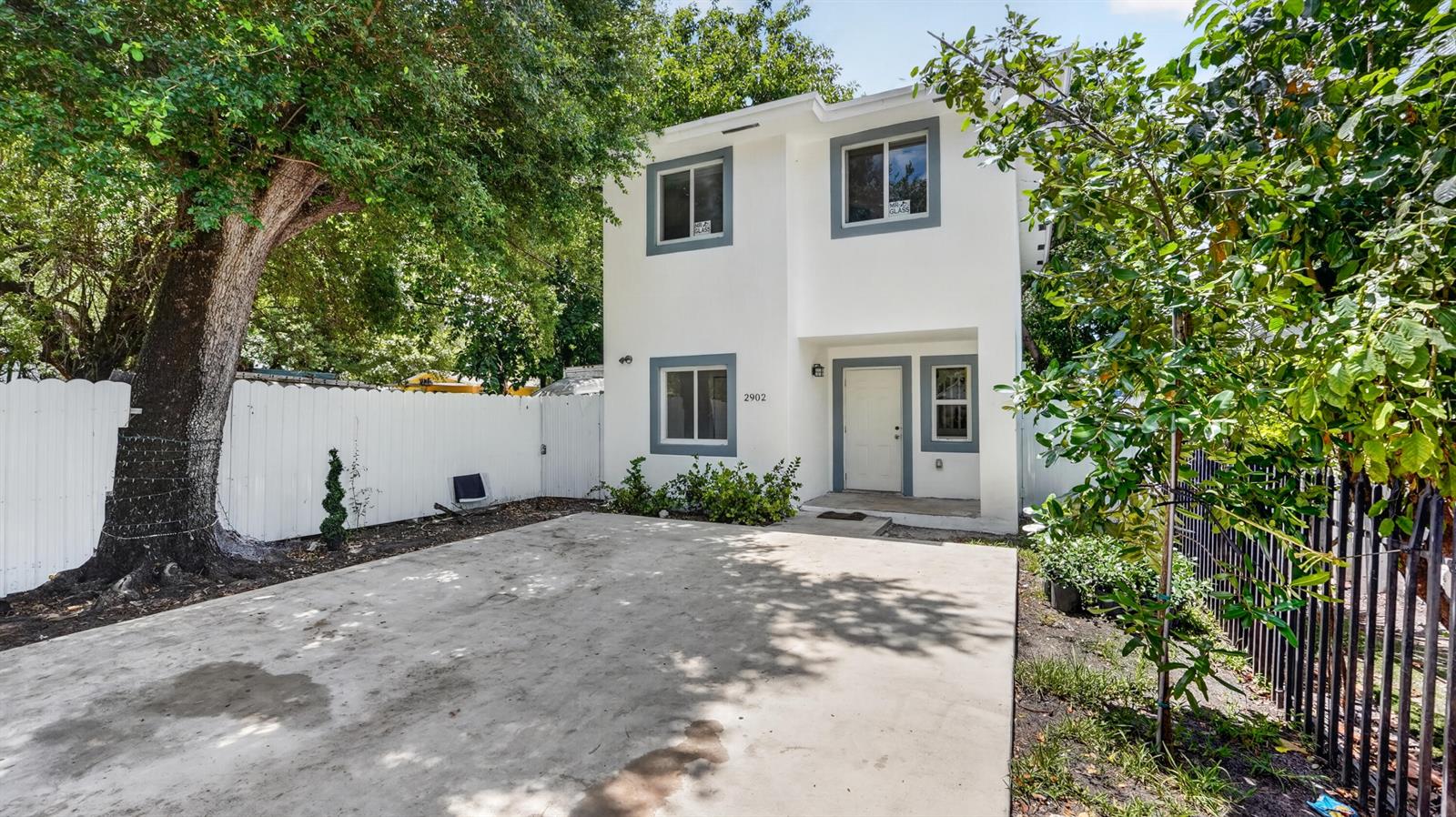 A two-story white house with gray trim features a concrete driveway and a white fence — 2902 NW 44th Street, Miami FL 33142, MIAMI, FL
