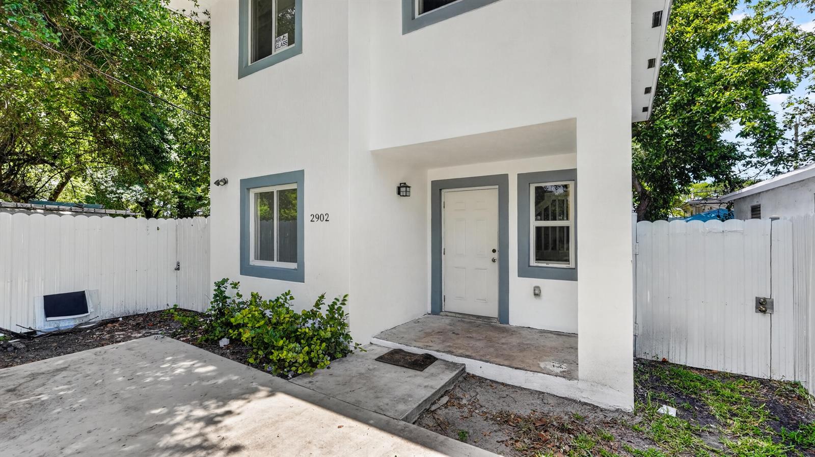 A two-story white house with a concrete driveway, a small front porch, and white fencing — 2902 NW 44th Street, Miami FL 33142, MIAMI, FL
