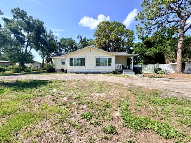 A single-story house with light yellow siding sits on a large, unpaved dirt lot — 420 53RD AVENUE E, BRADENTON, FL