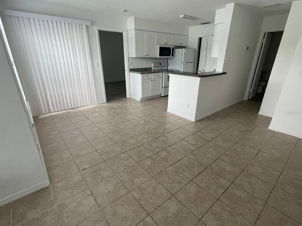 A bedroom with light wood-look flooring, a ceiling fan, and an open closet door — 1069 S HIAWASSEE ROAD UNIT 1322, ORLANDO, FL