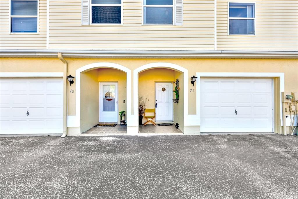 The exterior view shows two adjacent townhome units with white garage doors and arched entryways — 6400 46TH AVENUE N UNIT 71, KENNETH CITY, FL