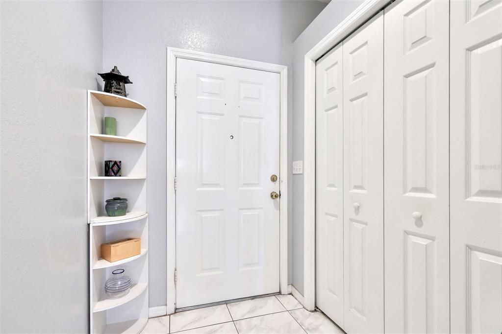 An entryway features a white door, a corner shelf, and white bi-fold closet doors — 6400 46TH AVENUE N UNIT 71, KENNETH CITY, FL
