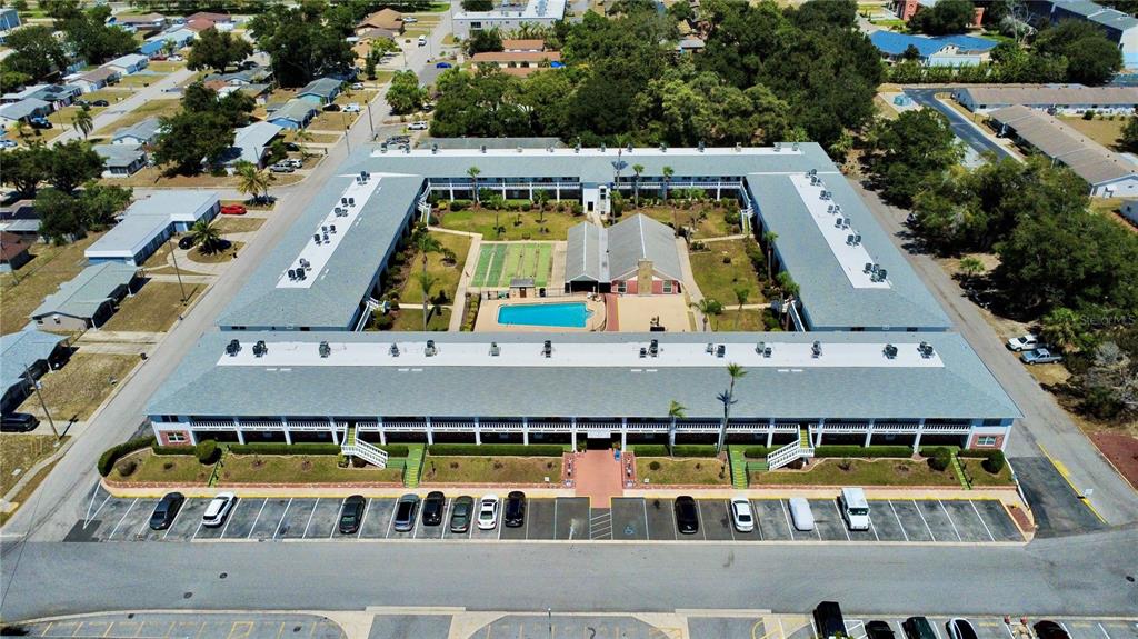 An aerial view shows a rectangular apartment complex with a central courtyard and swimming pool — 4746 AZALEA DRIVE UNIT 213, NEW PORT RICHEY, FL