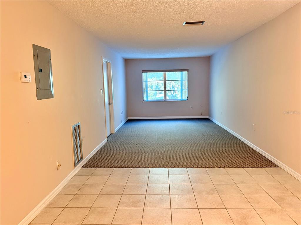 An interior view shows a room with a tiled foreground transitioning to a carpeted area — 4746 AZALEA DRIVE UNIT 213, NEW PORT RICHEY, FL