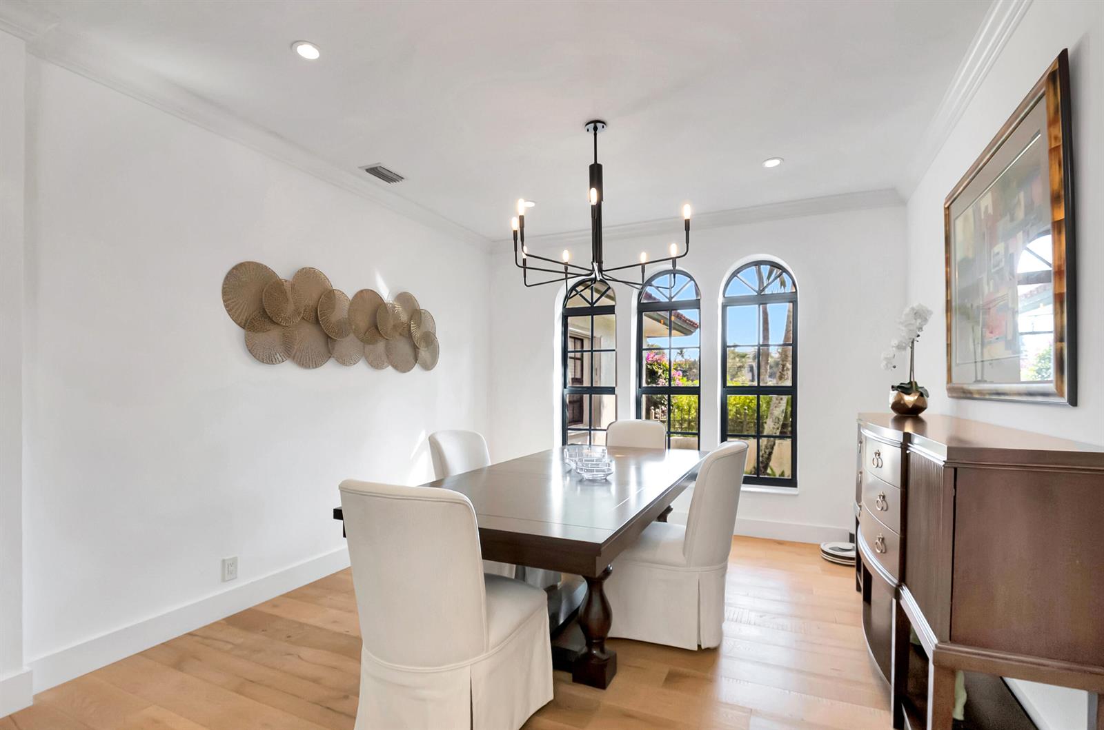 A dining room features a dark wood table, white slipcovered chairs, and three arched windows — 10321 El Paraiso Place S, Delray Beach FL 33446, DELRAY BEACH, FL