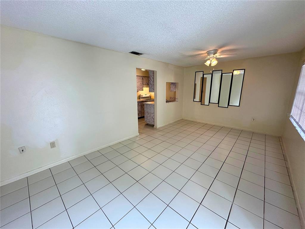 An empty room with white tile flooring, a ceiling fan, and a wall-mounted mirror — 325 N 5TH STREET UNIT 5, HAINES CITY, FL