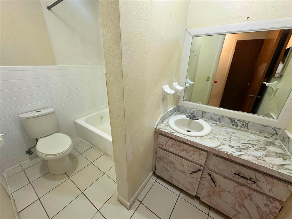 A bathroom features a white toilet, a bathtub, and a vanity with a marble-patterned countertop — 325 N 5TH STREET UNIT 5, HAINES CITY, FL