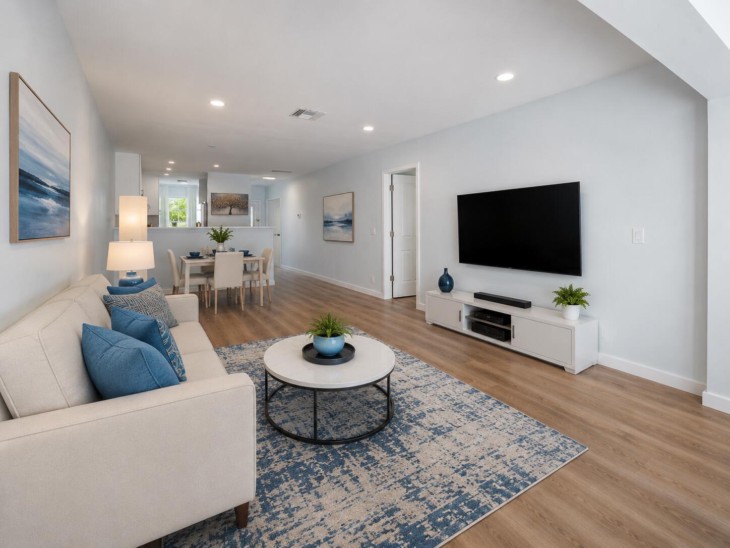 A living room with a beige sofa, blue area rug, and wall-mounted television — 1101 Cactus Terrace # 203, Delray Beach FL 33445, DELRAY BEACH, FL