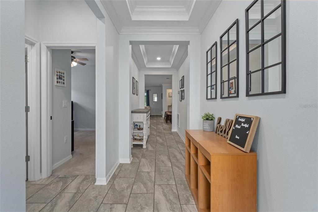 A bright hallway features light gray walls, tile flooring, and a tray ceiling — 12409 BRICK COBBLESTONE DRIVE, RIVERVIEW, FL