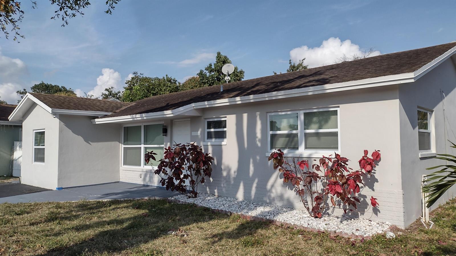 A single-story house with a light-colored exterior, white-trimmed windows, and red-leafed landscaping in front — 22682 SW 65th Circle, Boca Raton FL 33428, BOCA RATON, FL