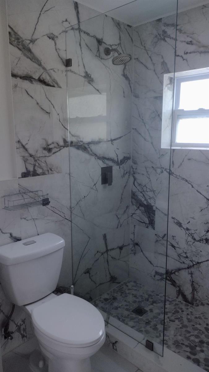 A bathroom features a glass-enclosed shower with marble-patterned tile walls and a pebble floor — 22682 SW 65th Circle, Boca Raton FL 33428, BOCA RATON, FL
