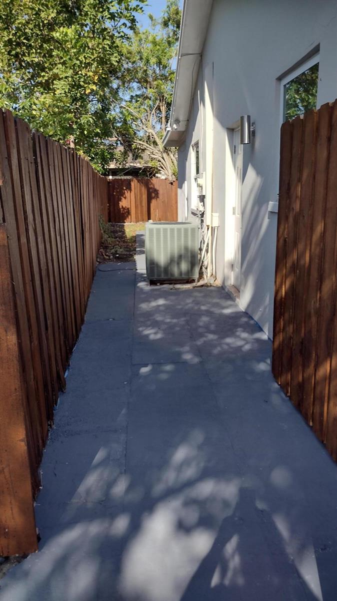 A narrow side yard with a concrete walkway, wooden fences, and an outdoor HVAC unit — 22682 SW 65th Circle, Boca Raton FL 33428, BOCA RATON, FL