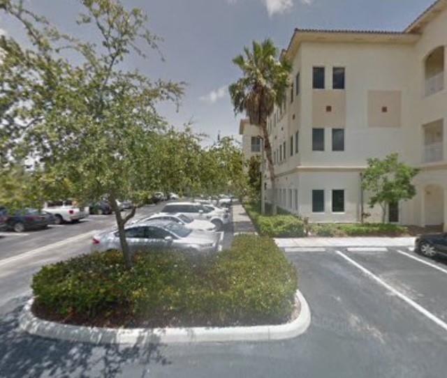 An exterior view of a multi-story building with a parking lot and landscaped shrubbery — 2893 Executive Park Drive # 105, Weston FL 33331, WESTON, FL
