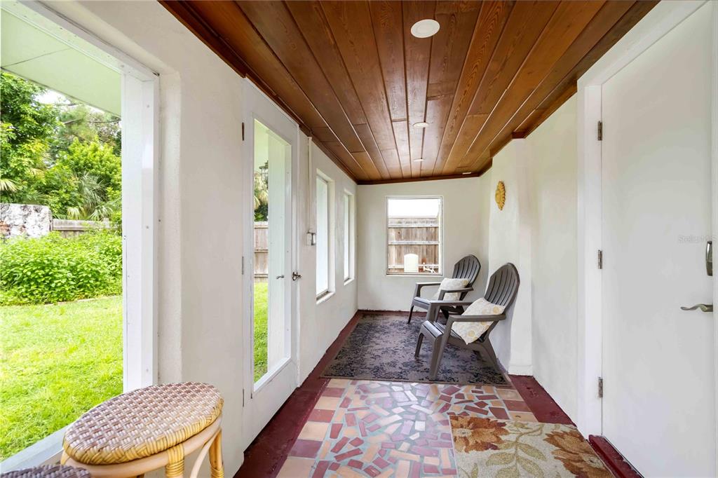 A sunroom features a wood-paneled ceiling, tiled floor, and two chairs facing a window — 2537 ASHTON ROAD, SARASOTA, FL